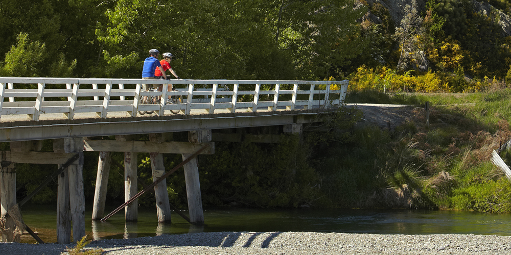 biker crossing a bridge in queenstown nz