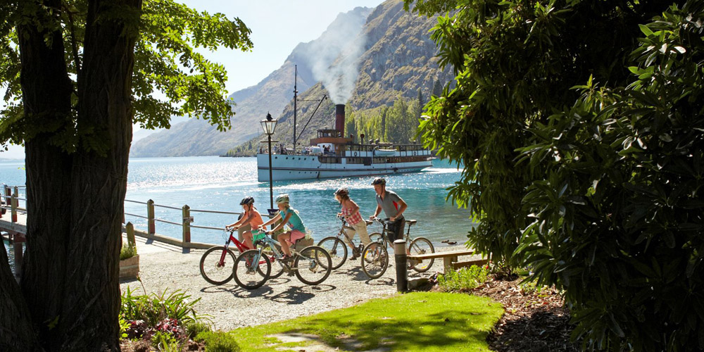 Real NZ TSS Earnslaw bike riders on track with TSS Earnslaw in the background